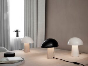 Fritz Hansen Night Owl bordlampe i både sort og hvid variant, placeret på et bord. Lampens organiske form og bløde lys skaber en hyggelig og stilfuld stemning i rummet.
