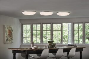 Tre LE KLINT Lamella 3 loftlamper i et moderne spiseområde, med plisserede skærme, der giver et blødt og jævnt lys.