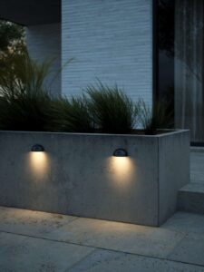 Nordlux Scorpius udendørslampe med halvmåneformet design, der skaber en behagelig og diffus belysning på husfacaden.