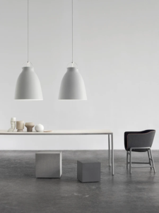 Caravaggio pendel i grå fra Fritz Hansen hængende over et spisebord i et minimalistisk interiør.