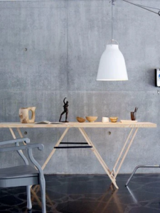 Hvid Caravaggio pendel fra Fritz Hansen monteret i et moderne rum med rå betonvæg.