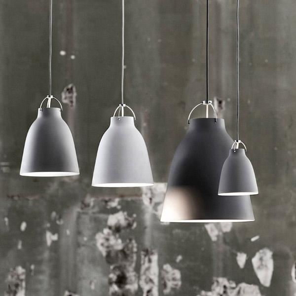 Flere Caravaggio pendler i forskellige størrelser og farver fra Fritz Hansen, hængende i et moderne rum.